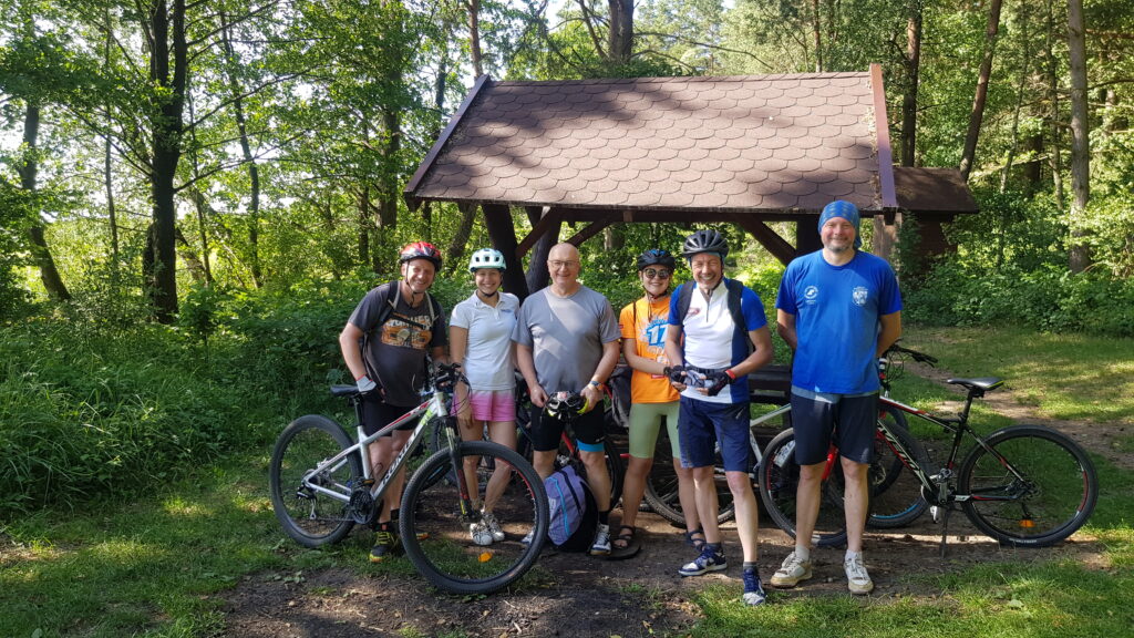 grupa sportowców w lesie, przed wiatą, z rowerami